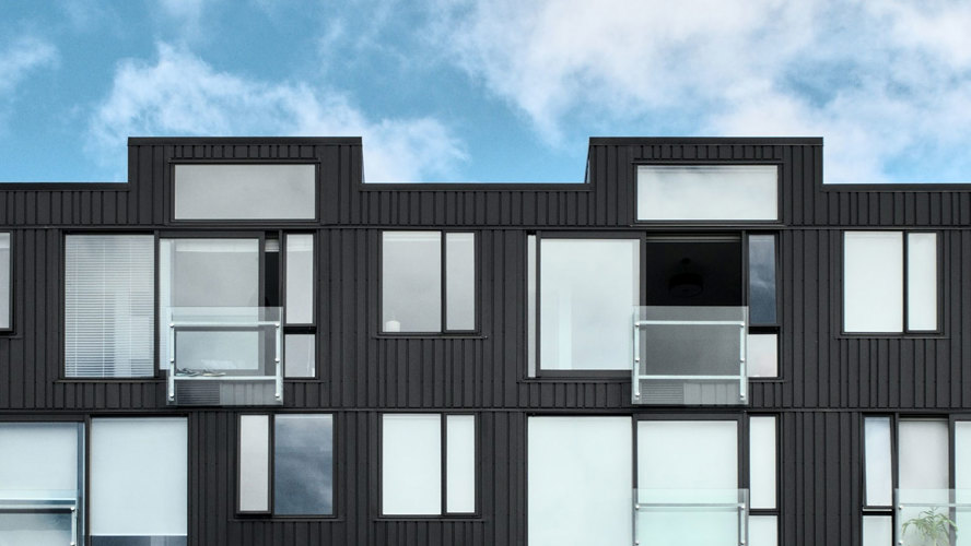 Svarta radhus i trä med stora fönster