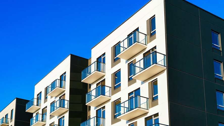 Vita lägenhetshus med beiga balkonger mot blå himmel