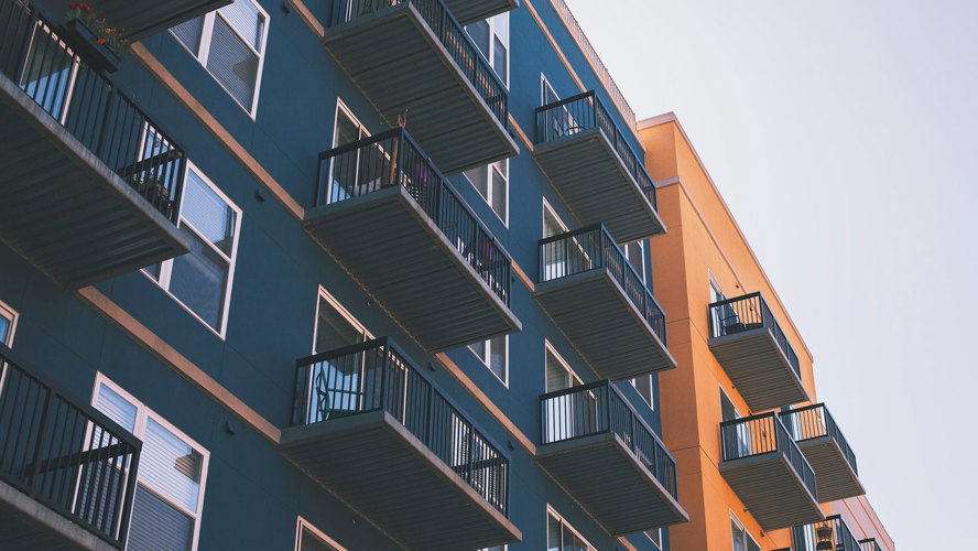 Mörkblått lägenhetshus med balkonger bredvid orange lägenhetshus.